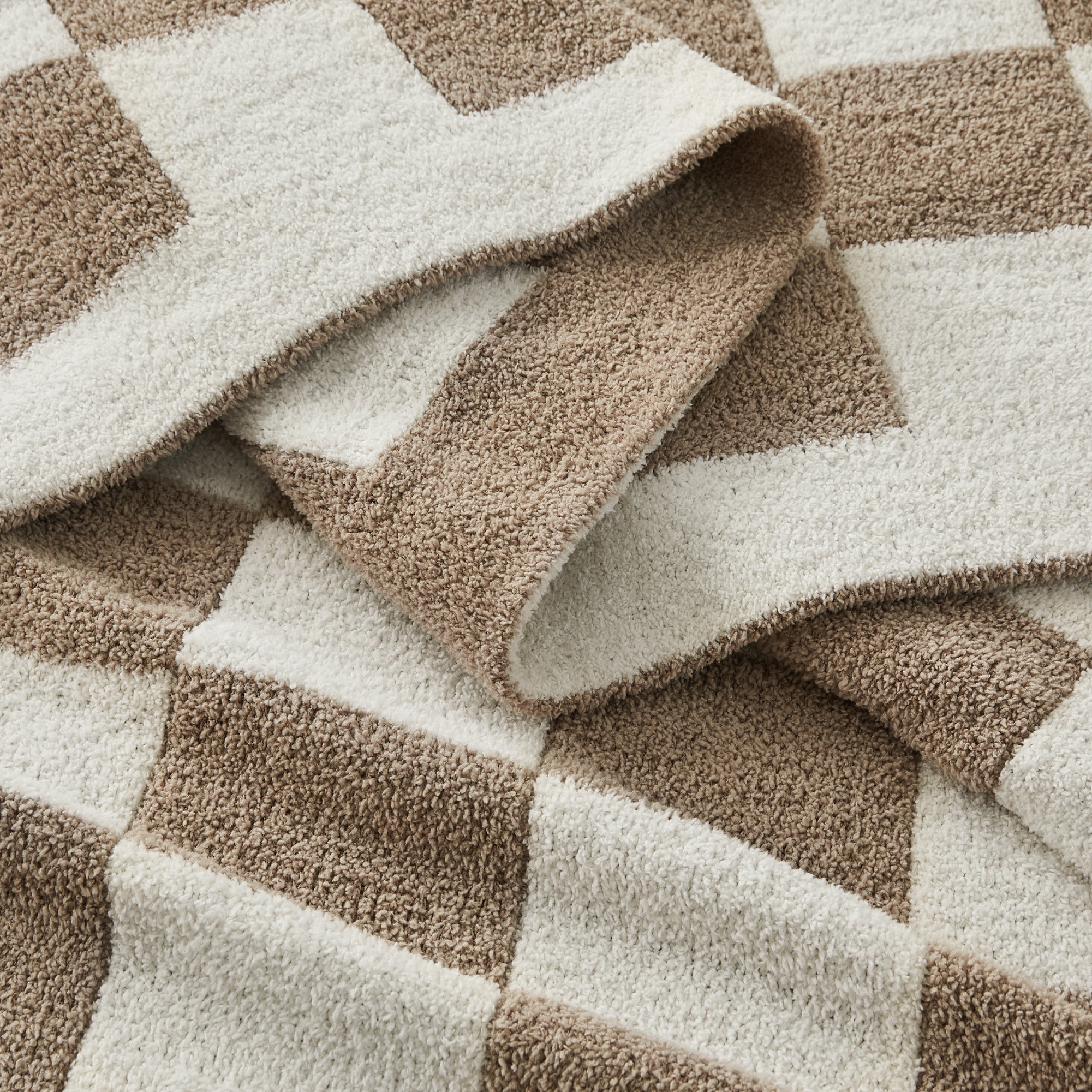 Litanika soft knit checkered throw blanket draped over a bed, cozy bedding accessory with a classic checkered pattern.