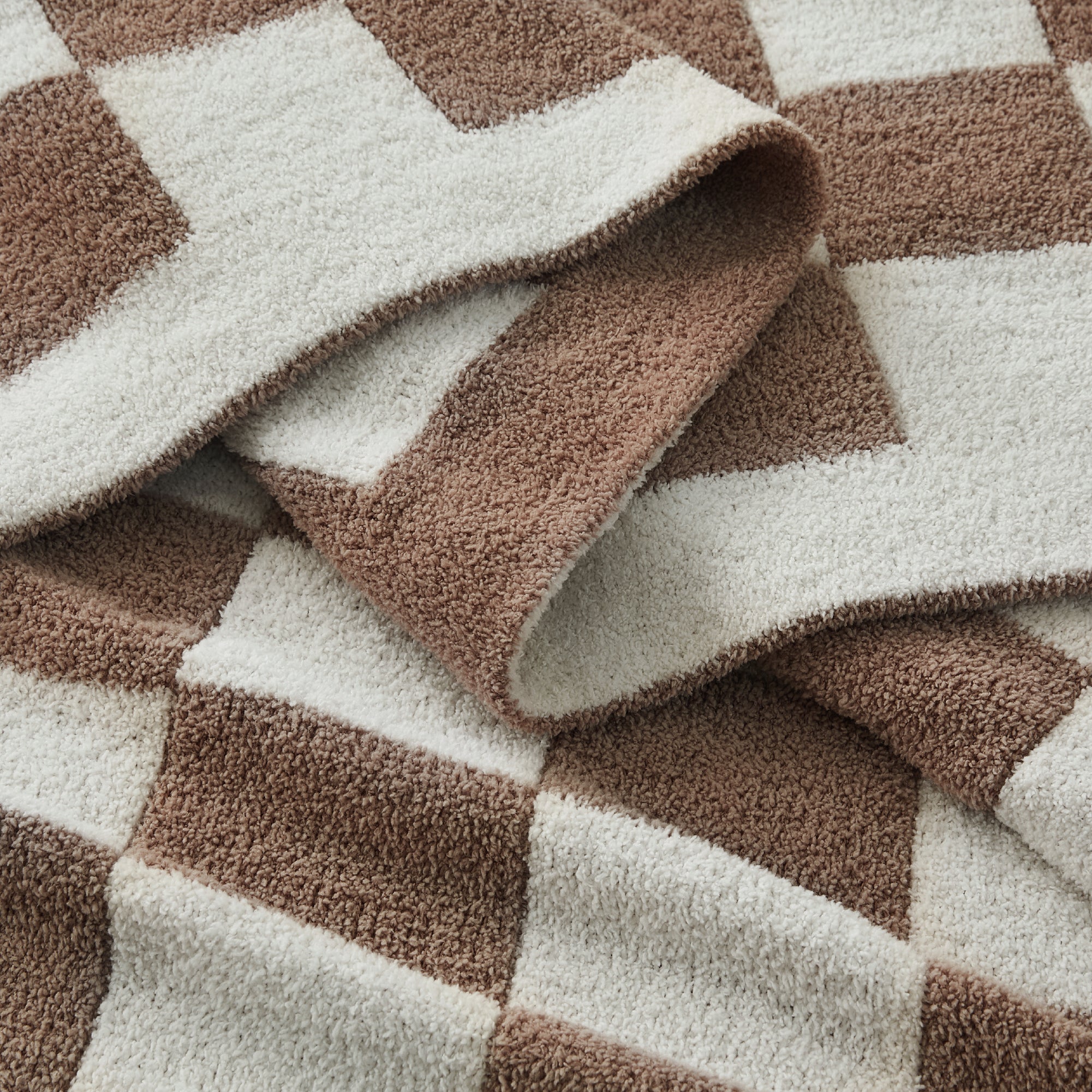 Litanika soft knit checkered throw blanket draped over a bed, showcasing cozy bedding with a classic checkered pattern.